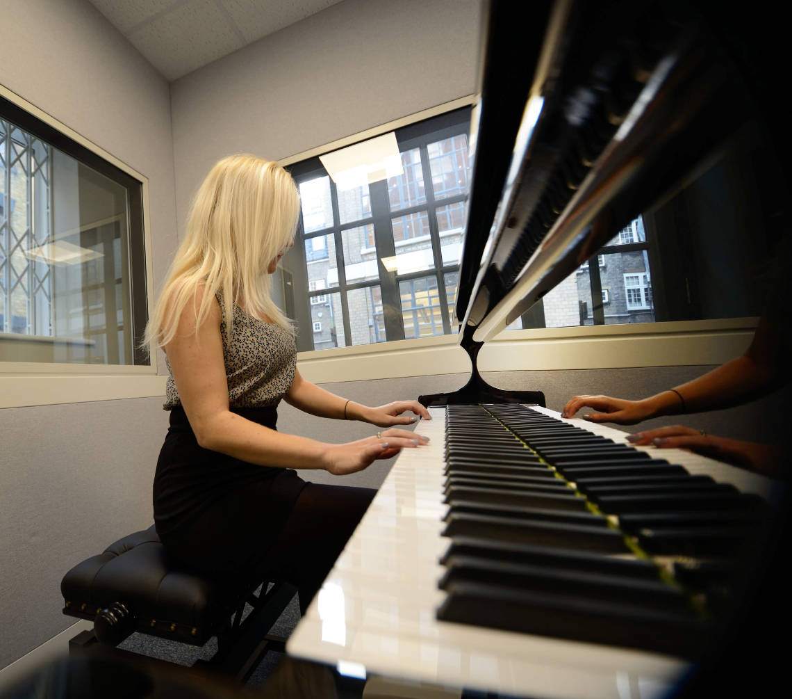 nainen istuu soittamassa pianoa
